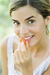 Woman eating cherry tomato, head and shoulders, close-up
