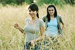 Young female hikers walking through field