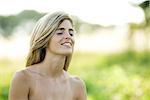 Young woman with bare shoulders, outdoors, eyes closed, smiling