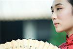 Jeune femme habillée en costume traditionnel chinois de tenir ventilateur, recadrée vue