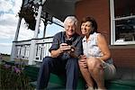 Couple with Electronic Organizer on Porch of Farmhouse