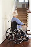 Haute femme en fauteuil roulant au bas de l'escalier