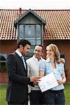 Couple With Real Estate Agent in Front of House