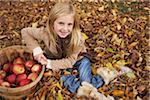 Portrait de Gril assis dans les feuilles d'automne avec panier de pommes