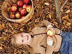 Porträt von Mädchen liegend im Herbst Blätter mit Korb Äpfel