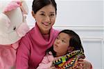 Mother and daughter with stuffed toy, smiling, portrait