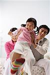 Young couple playing with their daughter in the bedroom