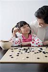 Young man and daughter playing weiqi game board, smiling