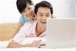 Young couple lying on bed and looking at laptop