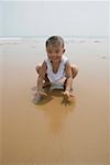 Boy playing in sand, smiling