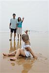 Boy waving goodbye to parents on beach