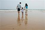 Parents with a son walking on beach, rear view