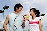 Young couple standing face to face with tennis racket and ball