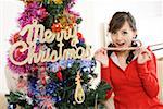 Portrait of a young woman sitting on sofa with candy cane by Christmas tree