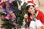 Portrait of a young woman with candy cane by Christmas tree