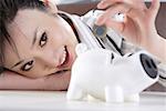 Young woman inserting coin in piggy bank