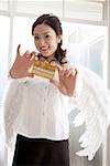 Portrait d'une jeune femme portant des ailes d'ange et tenant des cartes de crédit