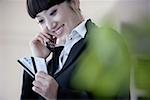 Close-up of a young woman using mobile phone and looking at credit cards