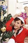 Portrait of young woman sitting by Christmas tree, smiling