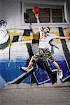 Young man playing basketball in front of graffiti