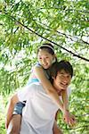 Young man giving woman piggyback ride, smiling, portrait