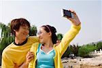 Young couple taking self portrait through mobile phone, smiling