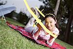 Portrait of young woman lying on front and holding glider