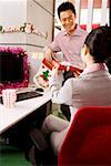 Businessman giving gift to businesswoman at office