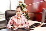 Portrait of a young woman sitting at desk in office