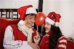 Young couple playing balloon together in Christmas hats