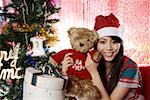 Young woman in Christmas hat holding a toy bear, smiling