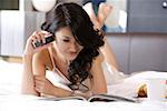 Young woman holding mobile phone and reading magazine, smiling