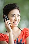 Young woman using mobile phone, smiling, close-up
