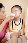 Mother feeding glass of milk to son