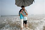 Jeune couple sur la plage avec parasol