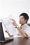 Young businessman reading newspaper at desk in office