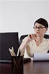 Young businesswoman sitting at desk, looking away