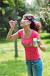 Young woman blowing bubbles in the park