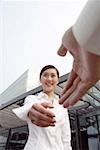 Businesswoman shaking hands, smiling, low angle view