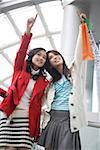 Young women standing at shopping mall and pointing