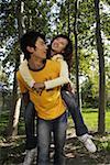 Young man giving woman piggyback ride, smiling