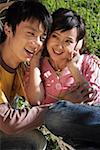 Young couple sit on a hammock and listening to music on headphones