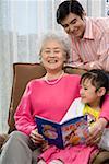 Grandmother,father and daughter reading at home