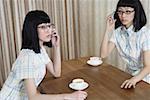 Young women using mobile phone by coffee cup