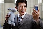 Close-up of a businessman holding toy and mobile phone