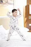 Boy standing on bed with arms raised