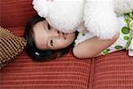 Portrait of a girl lying on sofa and holding toy