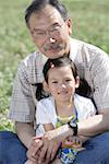 Fille assise avec grand-père sur champ