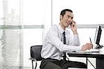 Young businessman using mobile phone in an office, smiling