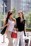 Zwei junge Frauen gehen mit Taschen
